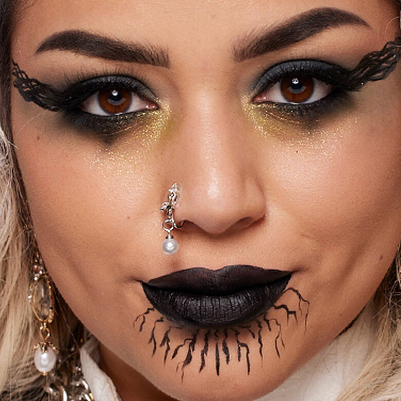 Look gotico di Halloween di NYX Professional Makeup con eyeliner sfumato e drammatico, rossetto nero, contouring scuro e piercing sul viso.