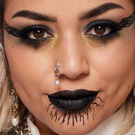 Look gotico di Halloween di NYX Professional Makeup con eyeliner sfumato e drammatico, rossetto nero, contouring scuro e piercing sul viso.