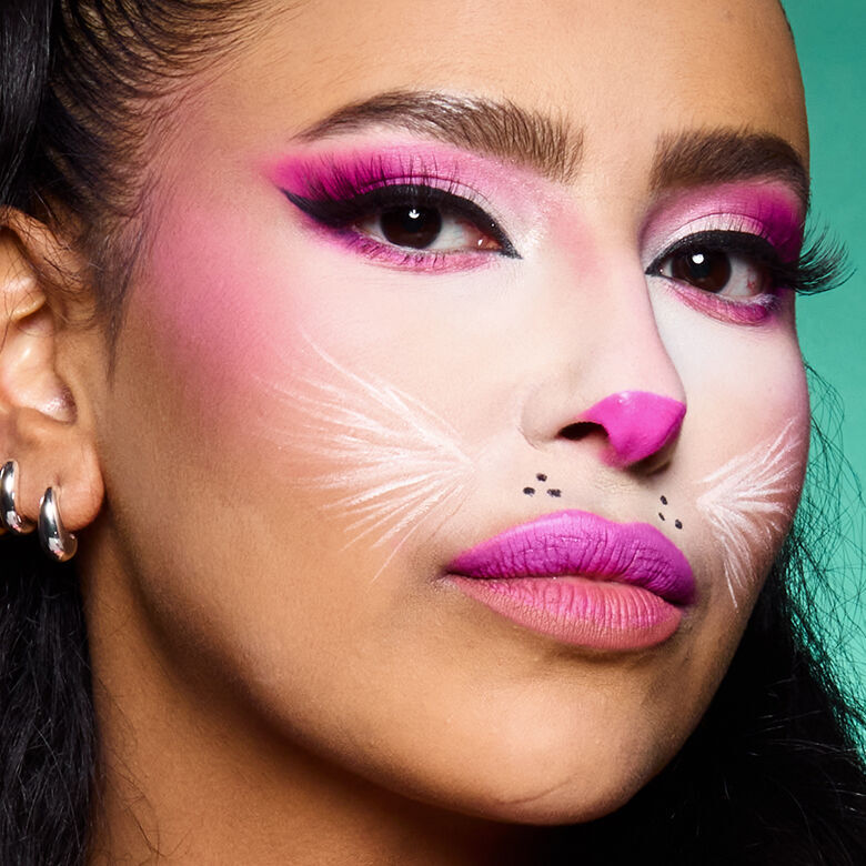 Look gatto rosa di Halloween di NYX Professional Makeup con trucco occhi rosa, musetto chiaro, dettagli di baffi e labbra rosa acceso.