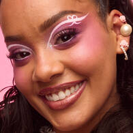 Look di Halloween rosa di NYX Professional Makeup con trucco occhi rosa glitterato, dettagli in strass e labbra rosa lucide.