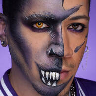Look teschio viola di Halloween di NYX Professional Makeup con pittura viso viola, occhi scuri smokey e denti dipinti di bianco.