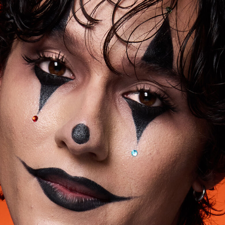 Look di Halloween di NYX Professional Makeup con pittura viso bianca, trucco occhi nero a ragnatela, lacrime nere e labbra effetto sangue rosso