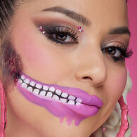 Look bambola di Halloween di NYX Professional Makeup con ombretto rosa, una bocca con effetto cerniera lampo rosa e applicazioni di perle sul viso.