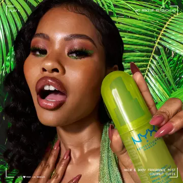 La modella tiene lo spray profumato capelli e corpo NYX Professional Makeup Coconut Cutie in un flacone verde neon su uno sfondo di foglie di palma tropicali