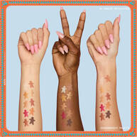 Presenta tre braccia con diverse tonalita di pelle, ognuna con swatch degli ombretti della NYX Professional Makeup Holiday Gingerbaddie Palette, per mostrare come i colori appaiono su differenti carnagioni.